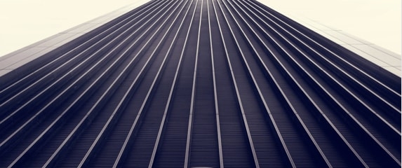 A low-angle view of a skyscraper with a repeating pattern of vertical lines, creating a sense of height and depth.