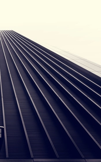 A low-angle view of a skyscraper with a repeating pattern of vertical lines, creating a sense of height and depth.