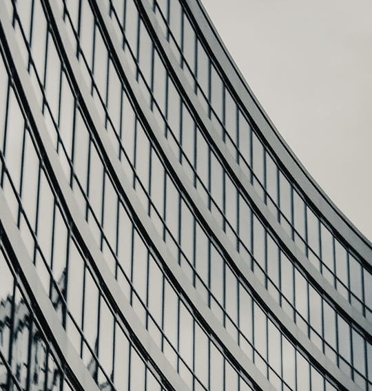 A close-up of a modern building with a curved facade and many windows, creating a repeating pattern.