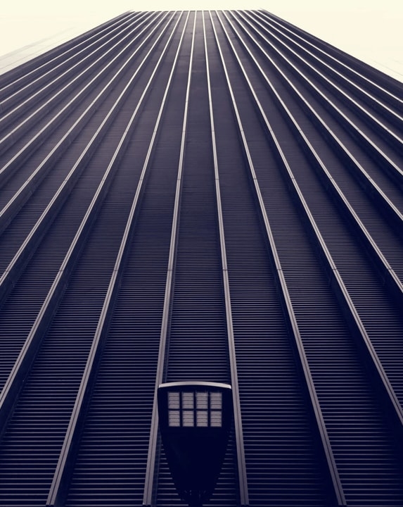 A low-angle view of a skyscraper with a repeating pattern of vertical lines, creating a sense of height and depth.