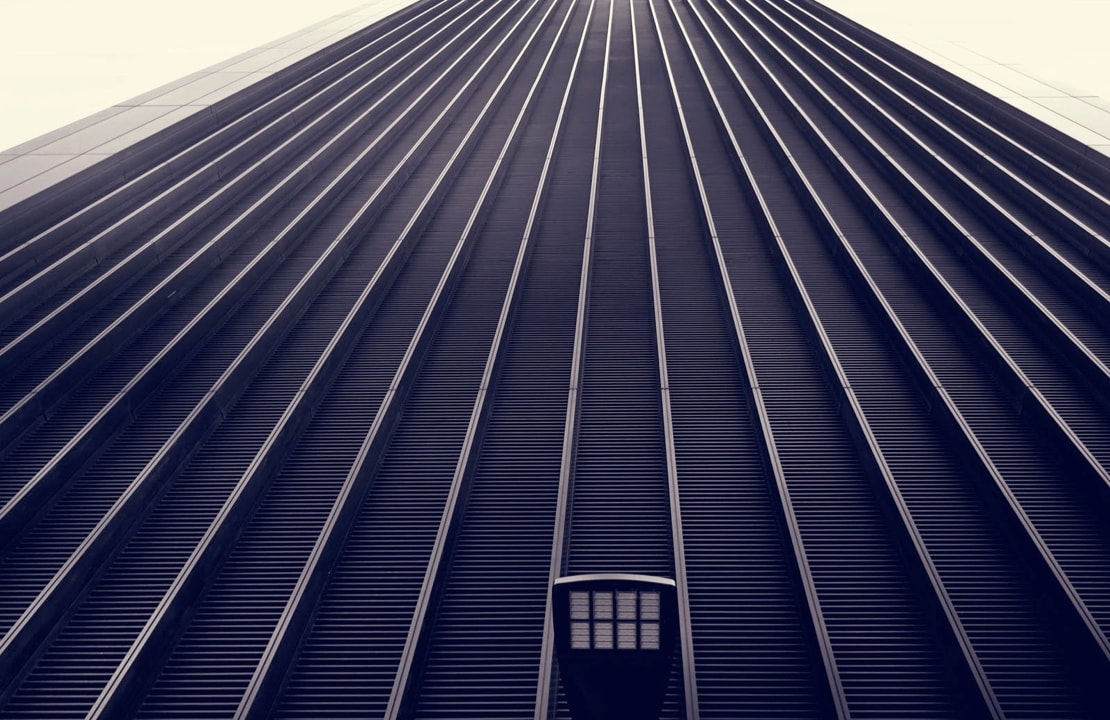 A low-angle view of a skyscraper with a repeating pattern of vertical lines, creating a sense of height and depth.