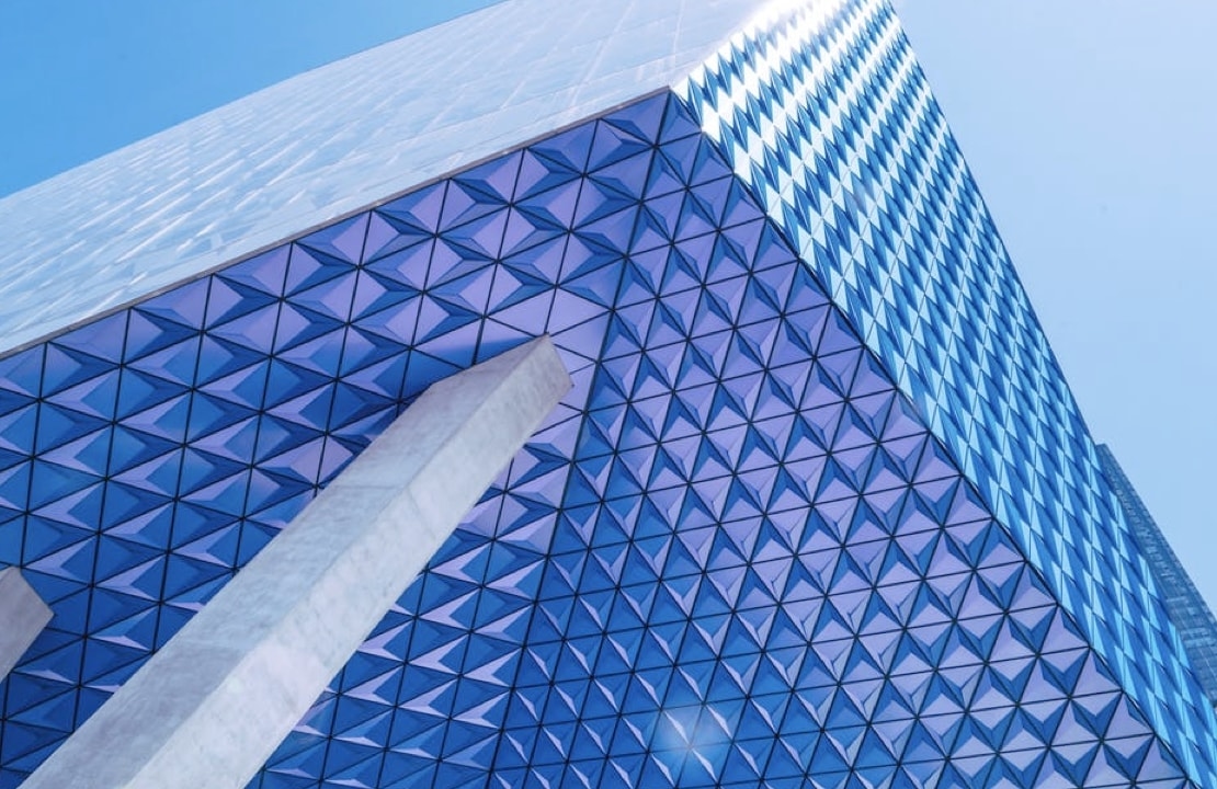 A modern skyscraper with a blue and white geometric pattern on its exterior, creating a sense of depth and dimension.