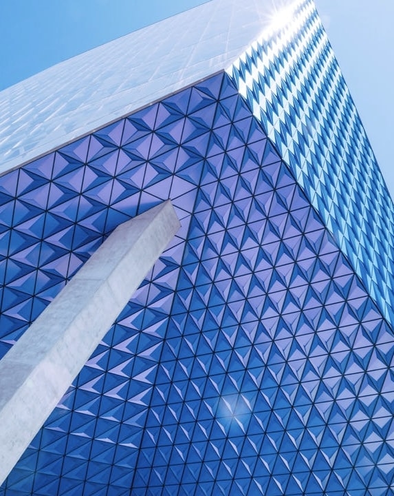 A modern skyscraper with a blue and white geometric pattern on its exterior, creating a sense of depth and dimension.