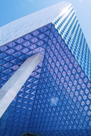 A modern skyscraper with a blue and white geometric pattern on its exterior, creating a sense of depth and dimension.