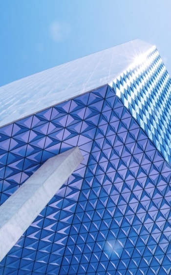 A modern skyscraper with a blue and white geometric pattern on its exterior, creating a sense of depth and dimension.