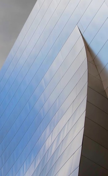 A close-up of a modern building with a curved, white facade and horizontal lines, creating a sense of depth and dimension.